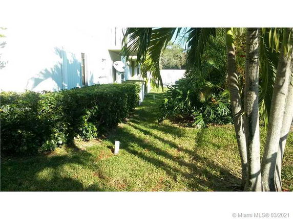 Side view of a building with adjacent garden area and trees.