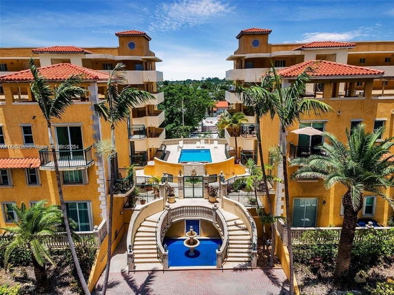 View of a multi-story building complex with a central swimming pool and surrounding balconies.