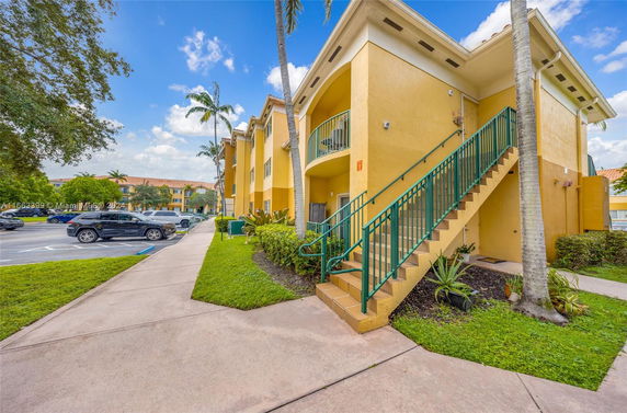 Front view of a yellow two-story apartment building with external staircases.