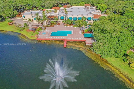 Aerial view of a building with multiple swimming pools and a lakeside fountain.