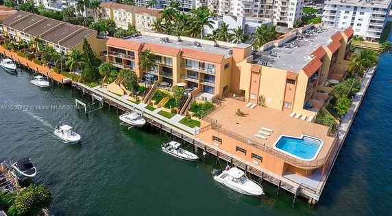 View of waterfront buildings with boats and a swimming pool.
