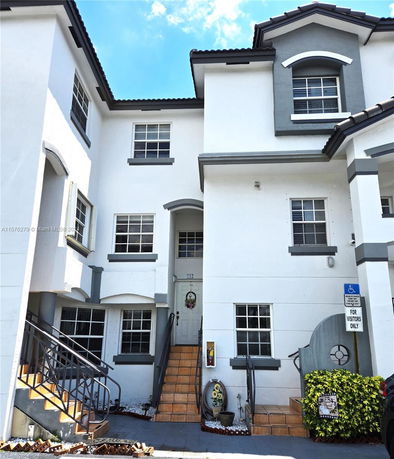 Front view of a multi-story residential building with stairs leading to the entrance.