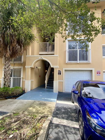 Front view of a multi-story building with an arched entrance and a garage.