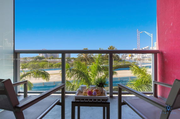 Balcony view featuring a cityscape and palm trees in the distance.