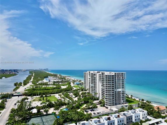 Panoramic view of coastal high-rise buildings with ocean and greenery.