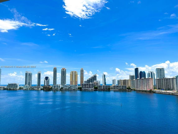Panoramic view of a city skyline with tall buildings and a body of water in the foreground.