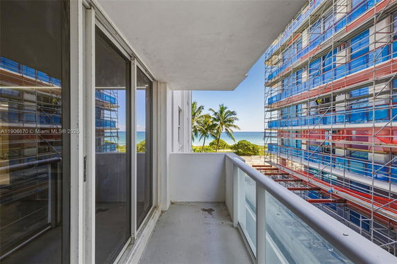 View from a balcony overlooking the ocean, with construction work on adjacent buildings.
