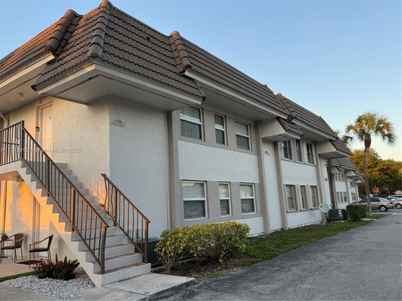 Front view of a two-story building with staircases and a tiled roof.