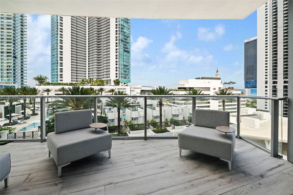Panoramic view from a balcony showing high-rise buildings and palm trees.