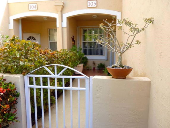 Front view of a building with individual unit entrances and a small garden.