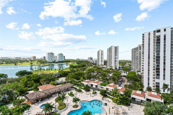 Panoramic view of high-rise buildings with a pool area in the foreground and a lake in the background.
