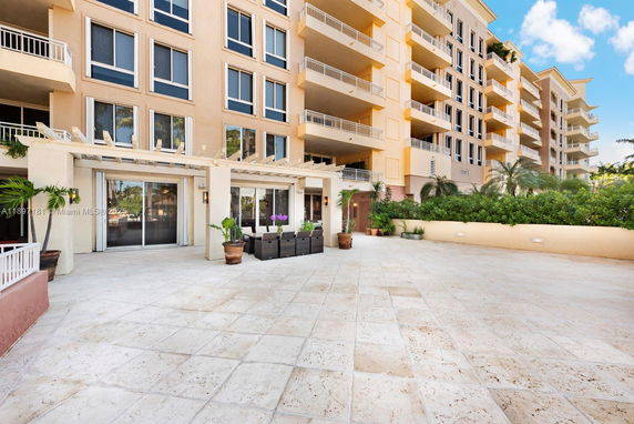 Front view of a multi-story apartment building with balconies and a large outdoor patio area.
