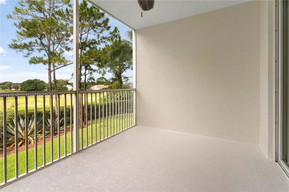 View from a balcony overlooking a grassy area with trees in the background.