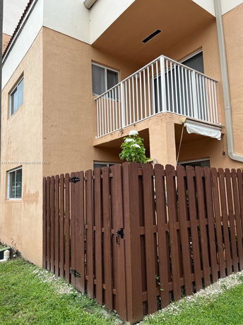 Front view of a two-story house with a small balcony and wooden fence.