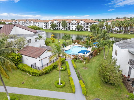 Aerial view of a swimming pool surrounded by residential buildings and greenery.