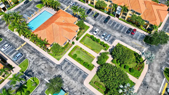 Aerial view of a building complex with a large swimming pool and adjacent parking area.