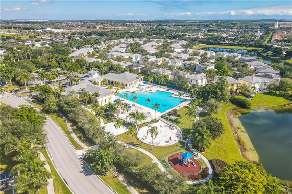 Aerial view of a neighborhood with a large swimming pool, community buildings, and surrounding houses.