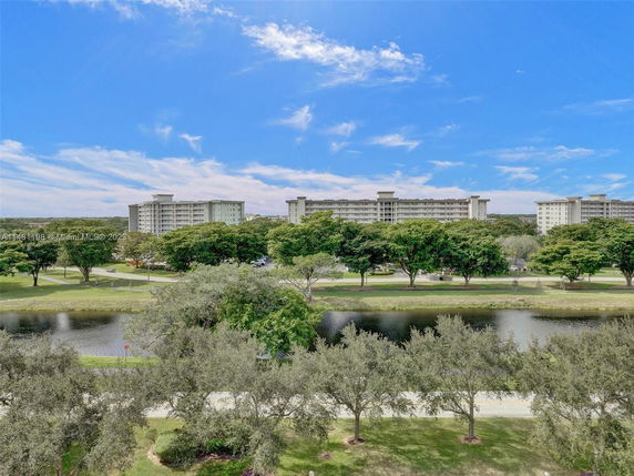 View of multiple multi-story residential buildings with a park and waterbody in foreground.
