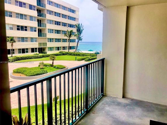 View from a balcony overlooking a multi-story residential building with ocean in the background.