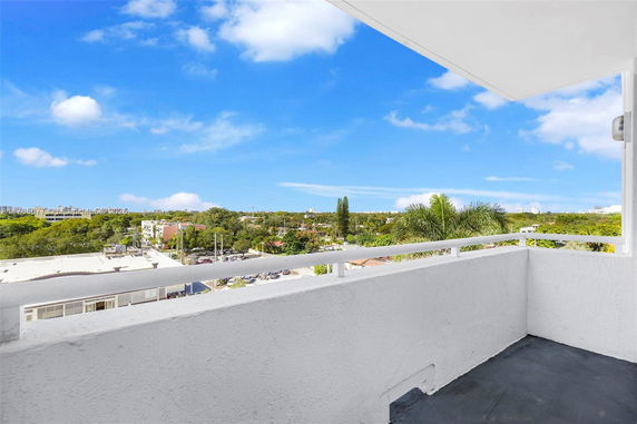 View from a balcony showing a scenic landscape with trees and buildings in the distance.