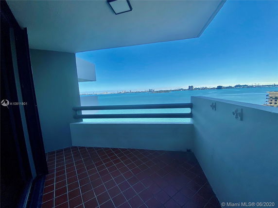 Outdoor balcony with a view of the water and city skyline in the distance.