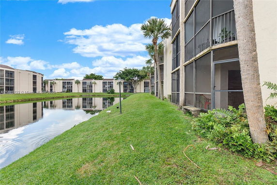 View of apartment buildings with screened balconies next to a pond.