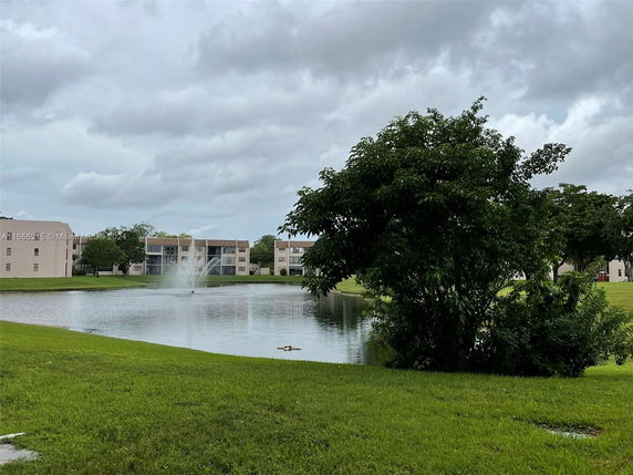 View of residential buildings with water fountain and greenery.