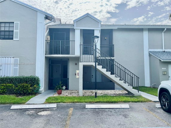 Front view of a two-story residential building with external staircase and parking area.