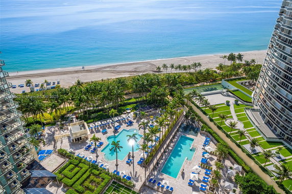 Panoramic view of a beachfront area with swimming pools and palm trees.