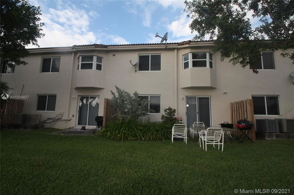 Backyard view of a two-story house with multiple bay windows and sliding glass doors.