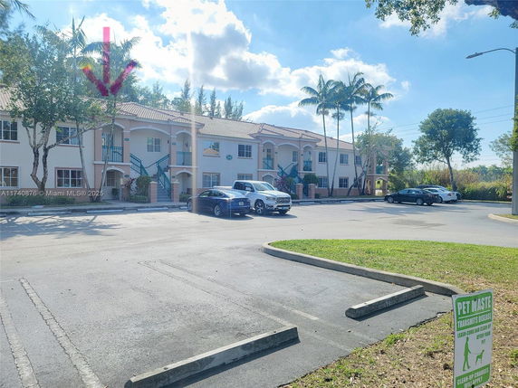 Front view of a two-story apartment complex with parking spaces in front.