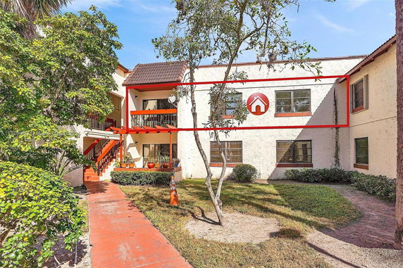 Front view of a two-story residential building with balconies and stairs.