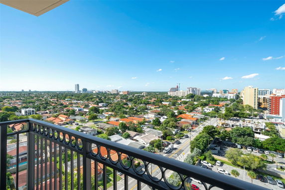 View from a balcony overlooking a cityscape with buildings and greenery.