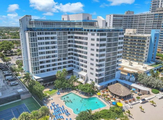 View of a multi-story building with a swimming pool area in front.