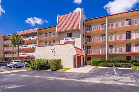 Front view of a multi-story residential building with balconies and a red roof.
