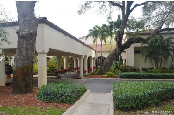 Front view of a building with arches and tiled roof, surrounded by greenery.