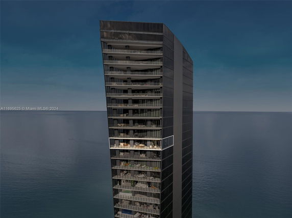 Front view of a modern multi-story building with a glass facade overlooking the ocean.