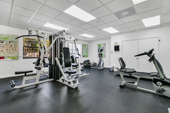 Room with exercise equipment including machines and weights in a gym setting.