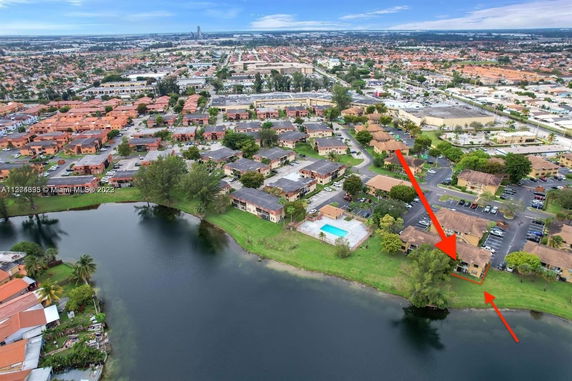 Aerial view of a residential area with a lake and multiple buildings.