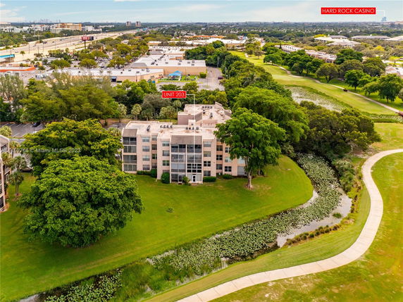 Aerial view of a residential building surrounded by greenery, with visible nearby roads and structures.