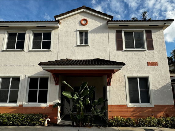 Front view of a two-story house with a tiled roof and multiple windows.