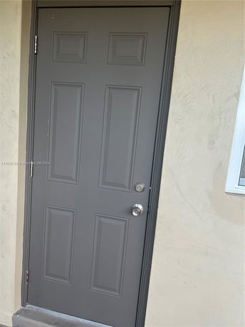 Front view of a gray door on a beige wall.