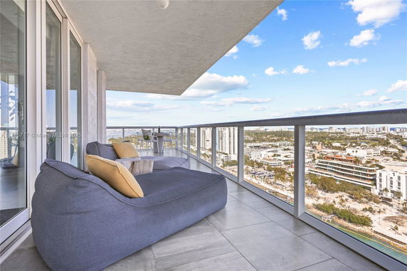 Balcony with seating overlooking cityscape with buildings and blue sky.