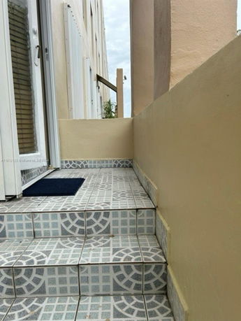Exterior steps leading to a door of a building with patterned tiles.