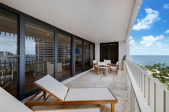 Panoramic view from a balcony overlooking the sea and nearby buildings.