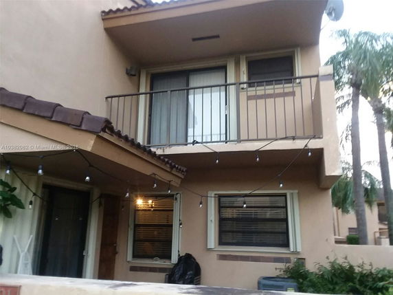 Front view of a two-story house with a balcony and string lights.