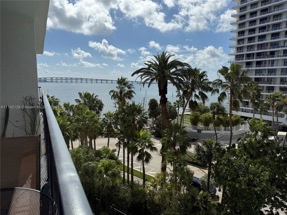 View of a cityscape with a waterfront and a distant bridge, seen from a balcony.