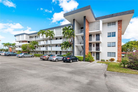 Front view of a multi-story residential building with balconies and parking area.