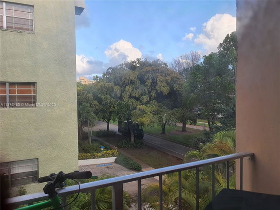 View from a balcony showing nearby trees and a road.
