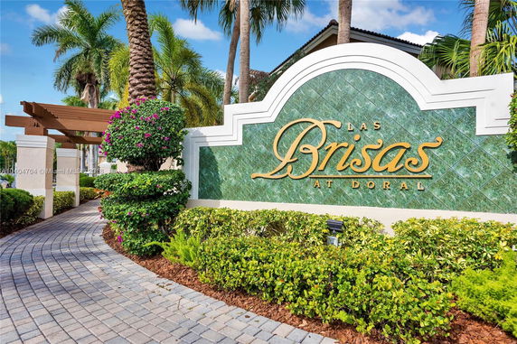 Front view of a building entrance with a decorative sign and greenery.